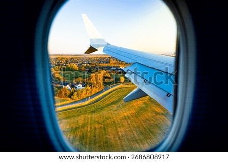 View from passenger plane window wing and jet engine over a road and fields in Denmark at sunrise, Copenhagen, travel concept.