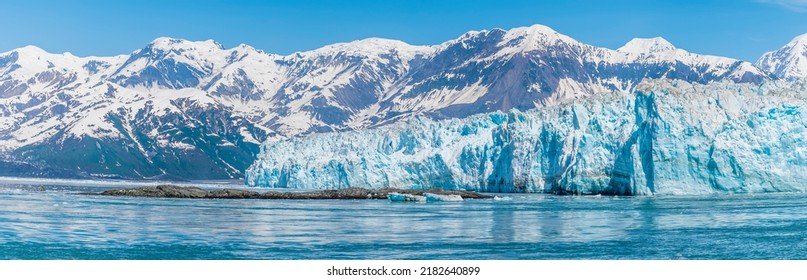 A view past an islet towards the Hubbard Glacier with mountain backdrop in Alaska in summertime - Shutterstock ID 2182640899