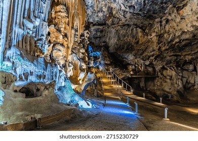 A view past limestone structures towards steps in a large chamber in Cango Caves, South Africa in springtime
