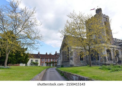 View Of A Path In An English Village With A Church, Village Green And Traditional Old Houses