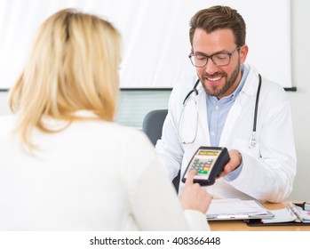 View Of A Patient Paying The Doctor By Credit Card