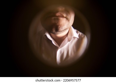 View from the peephole. A man in a white shirt is standing near the front door. The concept of breaking the law. Debt collection, collector. Close-up - Shutterstock ID 2206957577