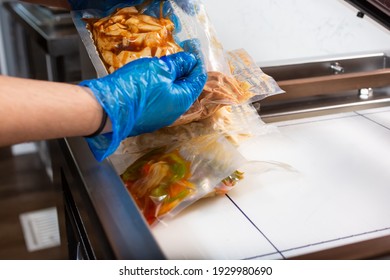 A View Of A Person Using A Vacuum Packing Machine, Used In The Industry To Seal Plastic Bags Of Food. Bags Of Meal Prep Are Being Prepared.