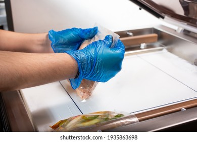 A View Of A Person Using A Vacuum Packing Machine, Used In The Industry To Seal Plastic Bags Of Food. Bags Of Meal Prep Are Being Prepared.