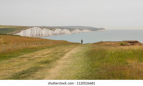 View of a person walking down a path towards the white cliffs of seven sisters in England, United kingdom