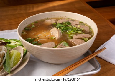 A View Of A Pho Soup Bowl With Meatballs, In A Restaurant Or Kitchen Setting.