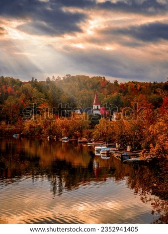 View of the picturesque village of Chelsea and its church during autumn, fall foliage with sunbeams piercing through clouds, Quebec, Canada. Photo taken in October 2022.