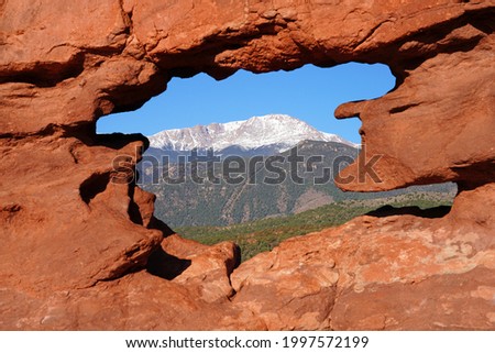 View of Pikes peak through the hole in the Siamese Twins red rock formation in the Garden of the Gods park in Colorado Springs, Colorado, United States
