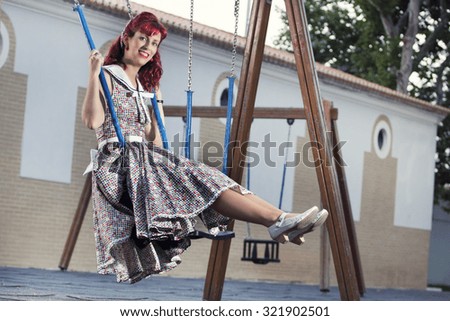 View of pinup young woman in vintage style clothing on a playground.