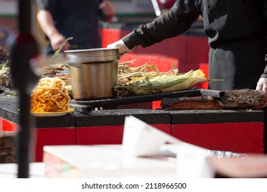 A View Of A Pit Master Preparing Corn On A Grill.