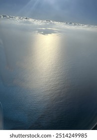 View from plane over ocean with clouds and water sun setting and night fall over the city 