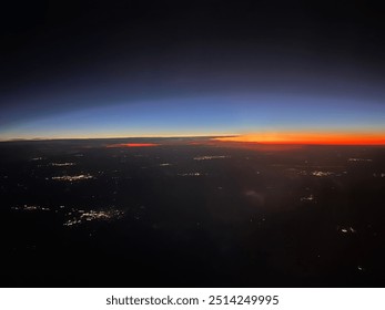View from plane over ocean with clouds and water sun setting and night fall over the city 