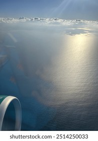 View from plane over ocean with clouds and water sun setting and night fall over the city 