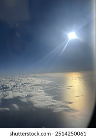 View from plane over ocean with clouds and water sun setting and night fall over the city 