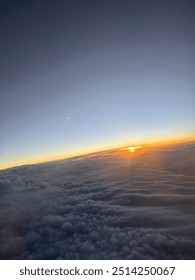 View from plane over ocean with clouds and water sun setting and night fall over the city 