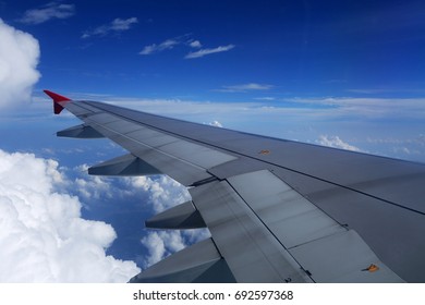 View from plane over the wing to clouds and ocean underneath.