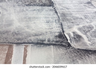 The View From The Plane Window To The Snowy Siberia. View Of The Snow-covered Fields. The Texture Of The Winter Landscape From The Side Of The Plane.