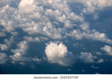 View from plane window of white rain clouds forming on blue sky. Air travel concept