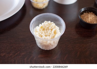 A View Of A Plastic Condiment Cup Of Small Crumble Cheese.