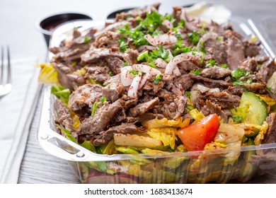 A View Of A Plastic Container Of Beef Shawarma Salad, In A Restaurant Or Kitchen Setting.