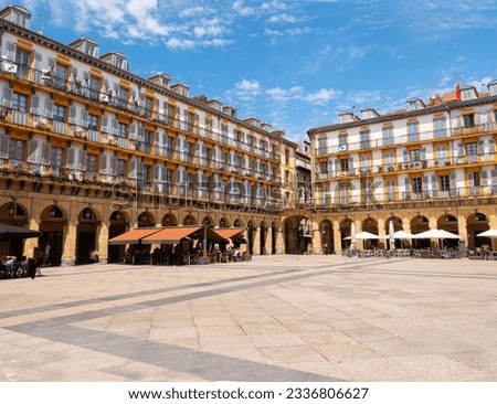 View of the Plaza de la Constitucion (Constitution Square) in heart of San Sebastian Old Town, Spain. Rectangular shape and surrounded by 4-storey arcaded buildings. Blue sky background.