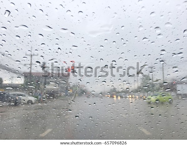 View point from car seat, blur photo of the\
intersection with traffic light and cars while raining. Water drops\
at widescreen.