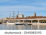 View of port and Malaga city. Cathedral (Santa Iglesia Catedral Basílica de la Encarnación), Andalusia, Spain. Palmeral de Las Sorpresas. Buildings, embankment, ship, vessels. Cityscape.