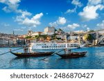 View of Porto city and Douro river with traditional boats with port wine barrels and sailing ship from famous tourist viewpoint Marginal de Gaia riverfront. Porto, Vila Nova de Gaia, Portugal