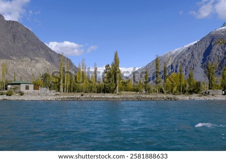 View of the pristine clear blue river against the majestic mountain range during the Fall season Ghizer Valley, Hunza, Gilgit Baltistan, Northern Pakistan.