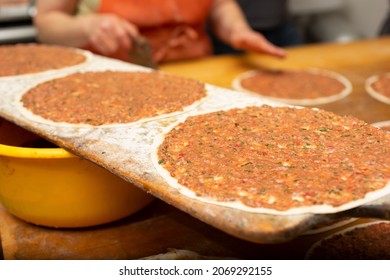 A View Of The Process Of Making Manakish On A Wood Table Surface, In A Restaurant Kitchen Setting.