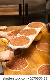 A View Of The Process Of Making Manakish On A Wood Table Surface, In A Restaurant Kitchen Setting.