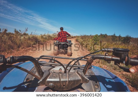 View from a quad bike in nature. Man in front driving off road on an all terrain vehicle. POV shot.