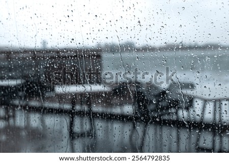 View of the raging sea through the window of the cafe. The waves are hitting the rocks. Autumn, rain, cloudy weather. 