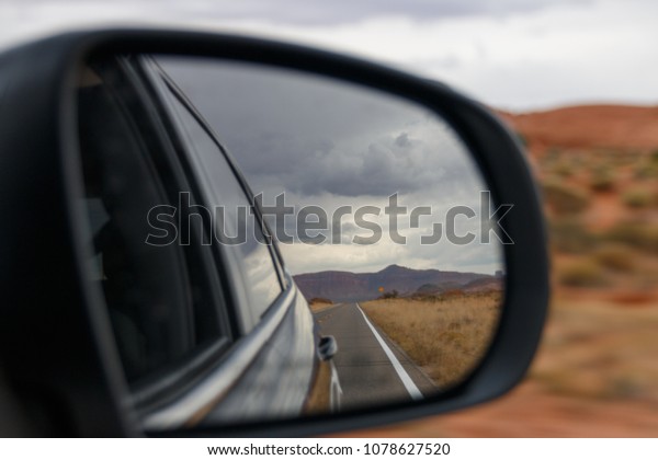 A view in a rear view mirror of a car driving in\
Utah, United States