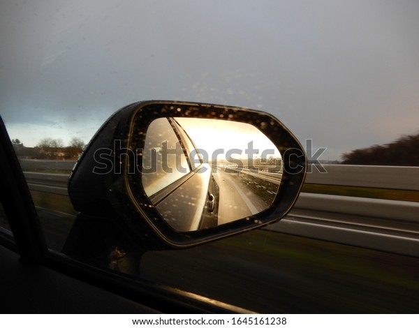 a\
view in the rear view mirror of a car with sun and\
dust