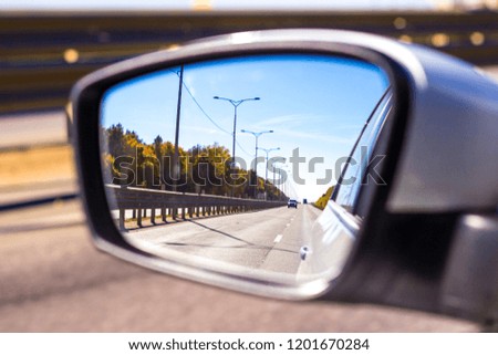 View in the rear mirror of a white car while driving on the autobahn. Auto travel.