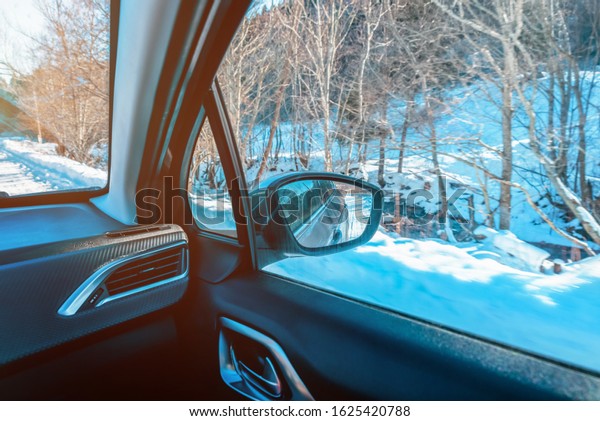 A view of the rearview\
mirror from inside the car. The concept of driving and traveling in\
winter