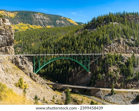 A view of the Red Cliff Bridge near Red Cliff, Colorado. The manmade green structure dominates the scene as it is set against the fall aspens. Its bright green color pulls the eye into the scene.