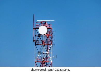 View of red and white communication tower against blue sky
