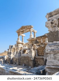 View of the remaining architectural elements and sculptures on the main street in the ancient city of Ephesus on a summer day in Izmir province, Turkey. 