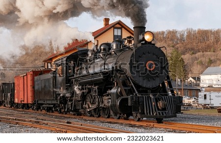 View of a Restored, Antique Steam Freight Train Approaching in Early Morning, on old Narrow Gauge Tracks on a Winter Day, Blowing Smoke