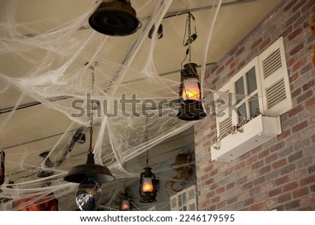A view of retro rustic lanterns among cobwebs and dead tree branches, part of a Halloween decoration landscape.