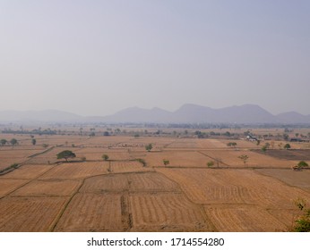 View Of The Rice Field After Harvest From A High Angle Overlooking The Mountains In The Background.Brown Arid Fields