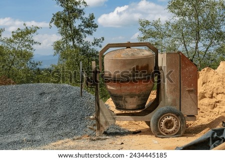 View of a rickety cement mixer flanked by sand and gravel, in a construction site near the colonial town of Villa de Leyva in central Colombia.