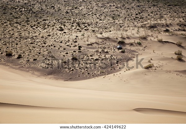View from the ridge\
of the Singing Dune to car parked below in desert national park\
Altyn-Emel, Kazakhstan