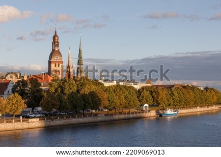 A view of Riga skyline and the Daugava River with the steeples of Riga Cathedral, St. Peter's Church and St. Saviour's Church In Riga Old Town visible behind the treelined riverbank