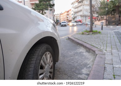 view of right front side of a white car and out of focus road in the front in city street