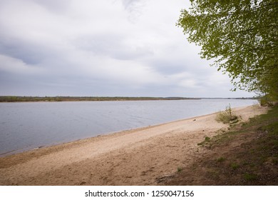 View of the river with a sandy beach. Empty beach. Heavy clouds in the cold season.