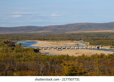 View of the river valley and the road bridge across the river. Transport and road infrastructure in Siberia and the Russian Far East. Ola river, Olsky district, Magadan region, Russia.