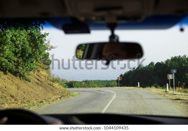 View of the road to the sea from the car.\
Rearview mirror and\
windshield